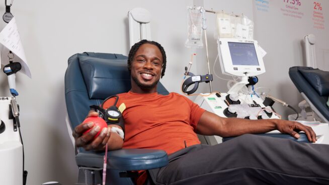 Smiling blood donor squeezing a foam heart