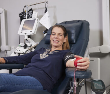 A CBC blood donor squeezing a red foam heart as she donates blood.