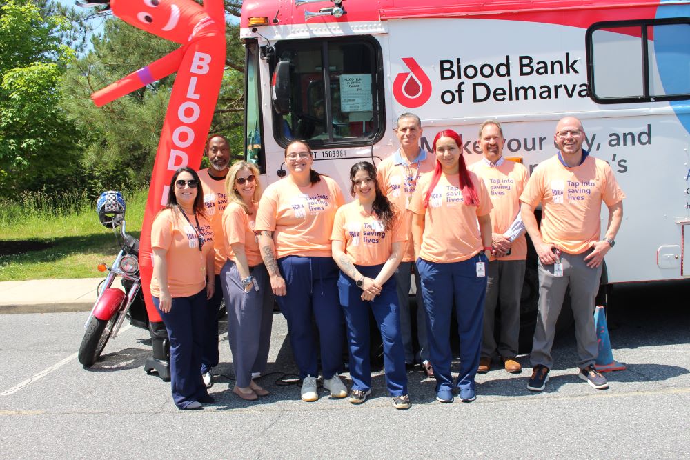 BBD staff posing in front of the mobile bus at Dogfish Head Brewery Blood for a Brew Blood Drive.